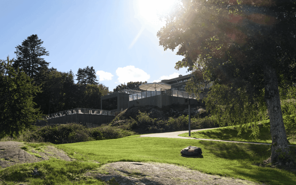 Rasenroboter mäht große Grünfläche bei moderner Anlage im Innviertel mit Hanglage